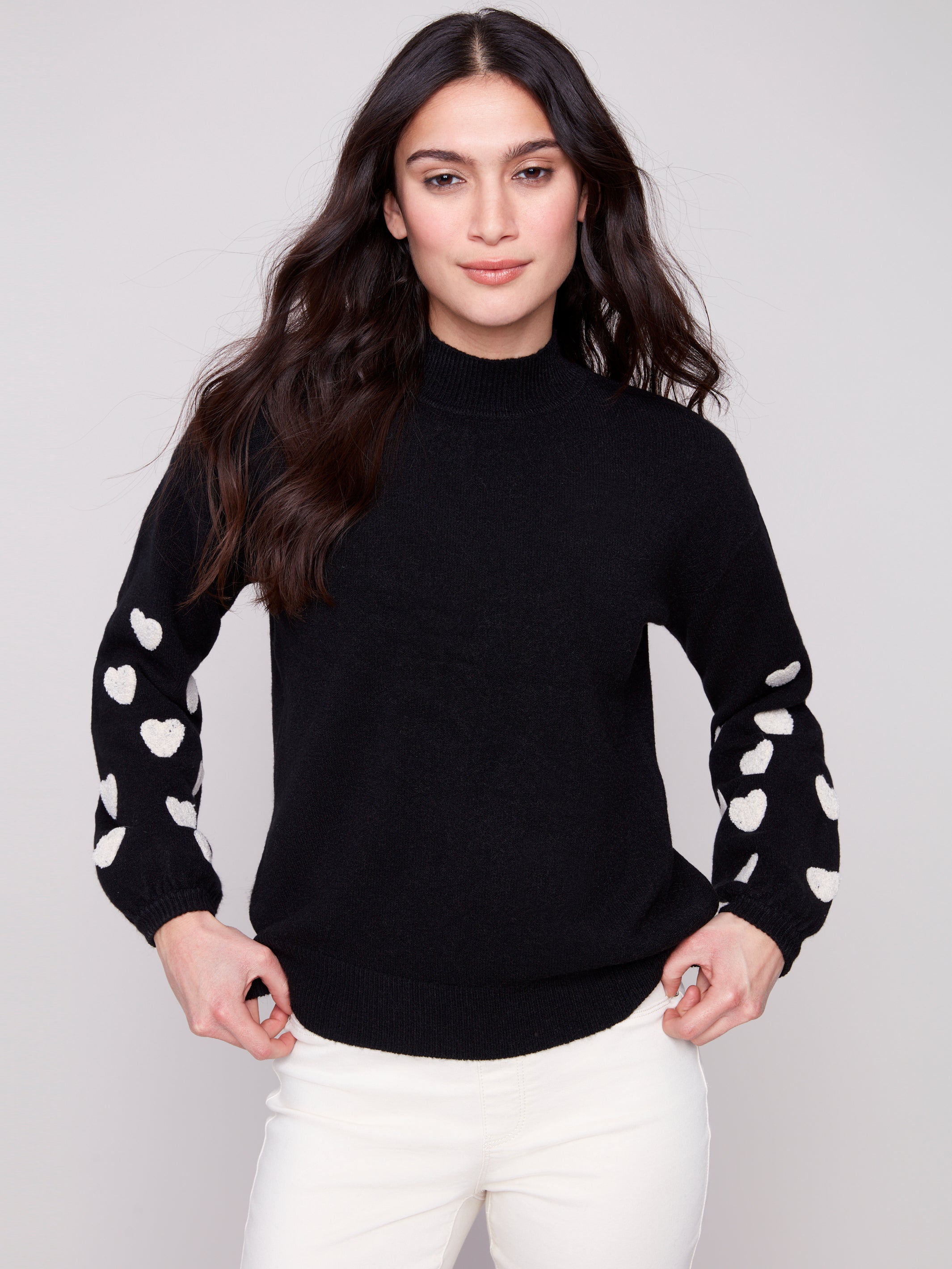 Pearls Boutique | Port Dover Ontario|Charlie B | Mock Neck Sweater With Embroidered Hearts| colour black with white embroidered hearts on sleeves. Mock neck sweater in a soft plush knit, featuring heart embroidery on balloon sleeves, relaxed fit.