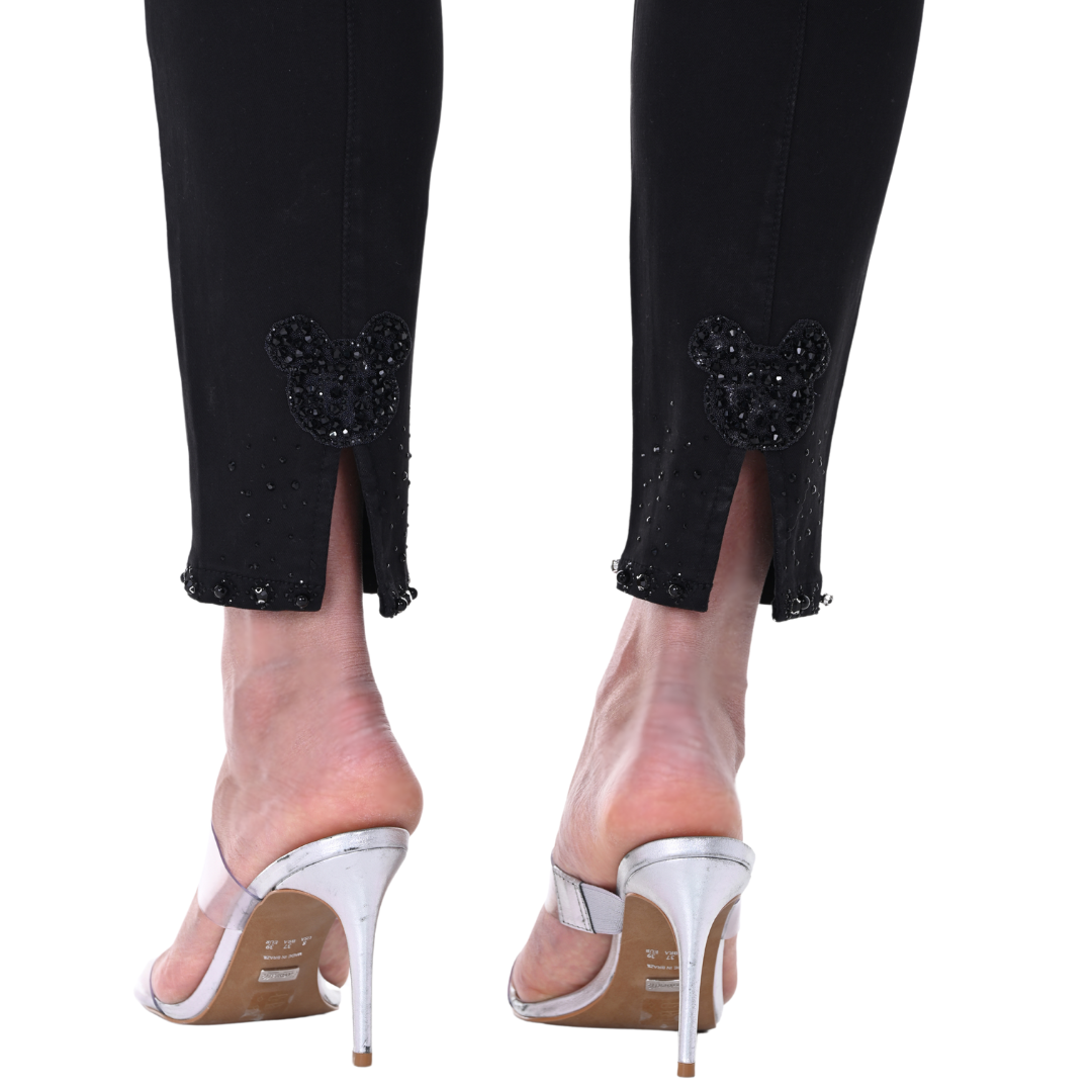 Pearls Boutique - Port Dover Ontario - Frank Lyman Black Denim Pant Ideal for the fashion-forward woman who values whimsical details Features a straight leg, high rise, and chic fly front for a timeless silhouette Hem adorned with rhinestone detailing for a touch of sparkle Back hem boasts a playful Mickey Mouse slit detail for added fun Ankle cut for a perfect blend of sophistication and playfulness A flawless addition to your fashion repertoire.