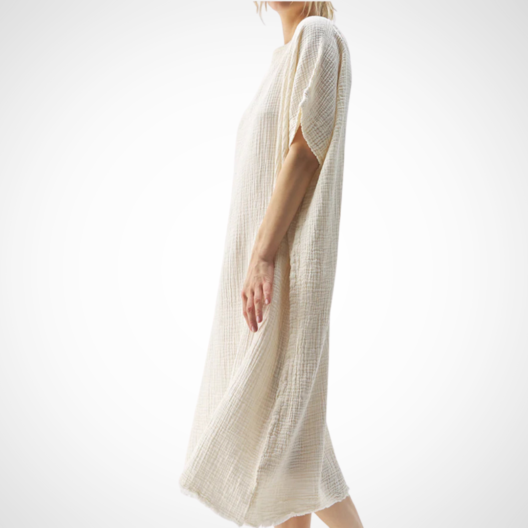 Pearls Boutique - Port Dover Ontario -Pokoloko - Crinkle Balloon Dress. Cream Coloured. Crinkle Balloon Dress: Features a boat neckline, Mid-calf length and one-size-fits-most design make it a versatile capsule wardrobe essential. Crafted from pure Turkish cotton using a special weaving technique for a crinkle appearance and enhanced softness. Available in two color stories: cream and black, with the black variants garment-dyed for a vintage-style distressed look. Responsibly made and consciously designed.