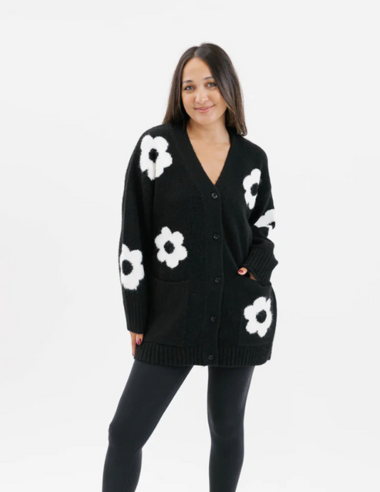 PearlsBoutique-PortDoverOntario-Smash_Tess-FloralCardigan-Black with white flowers 
Meet FLORA: The Adorable Button-Down Cardigan!

Made from ultra-soft eyelash yarn
Features a sweet floral intarsia design
Relaxed fit with full-length sleeves
Handy patch pockets for added function
Longer length for ideal bum coverage
Stylish, cozy, and perfect for layering
Updated version of our best-selling cardigan
Fabric:

53% Polyester, 39% Acrylic, 5% Wool, 3% Spandex