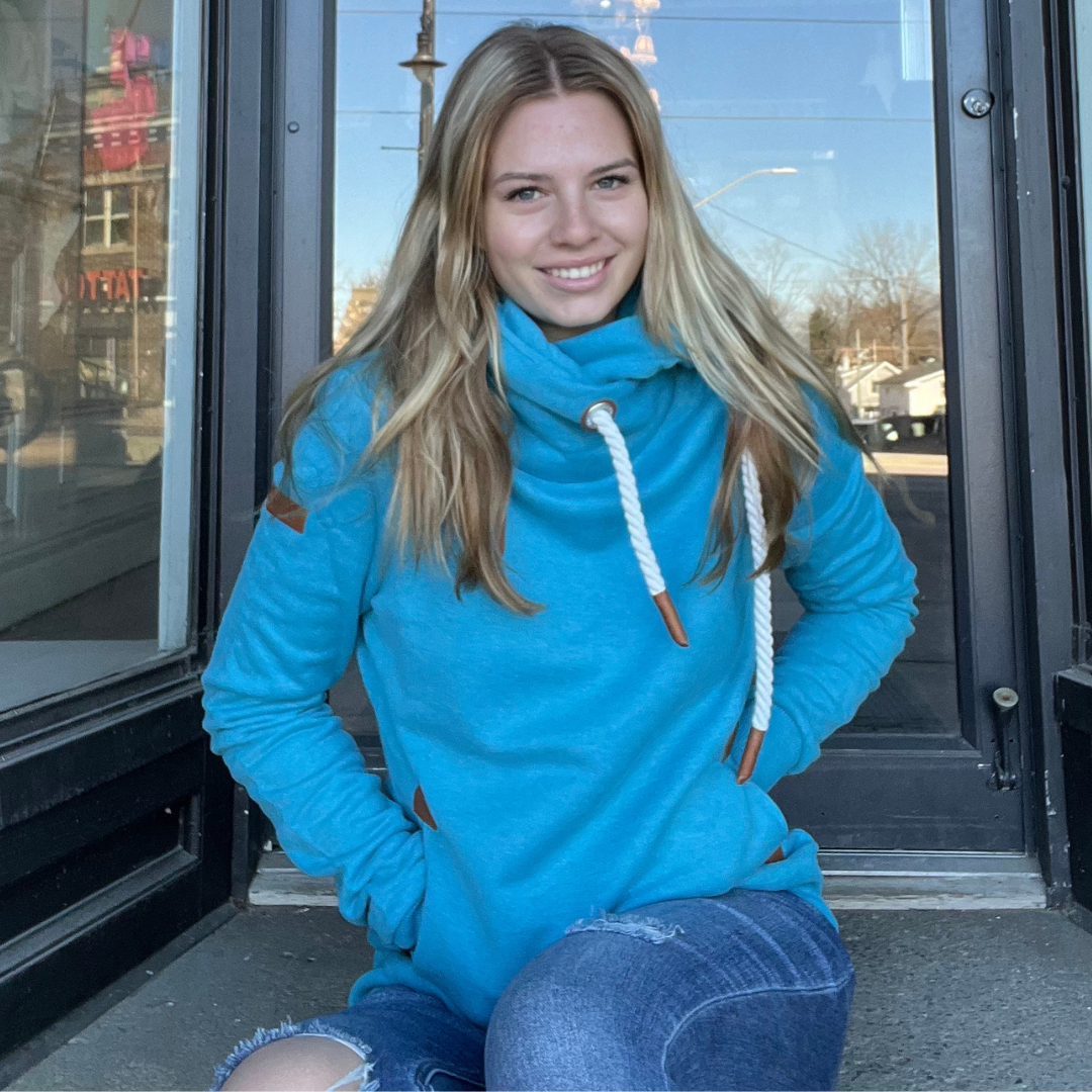 Pearls Boutique - Port Dover Ontario - Wanakome - Artemis Hoodie.  colour lagoon blue . Women’s Wanakome Artemis sweatshirt with cowl neck and rope drawstrings,  heavy fleece with vegan leather accents and front pockets."