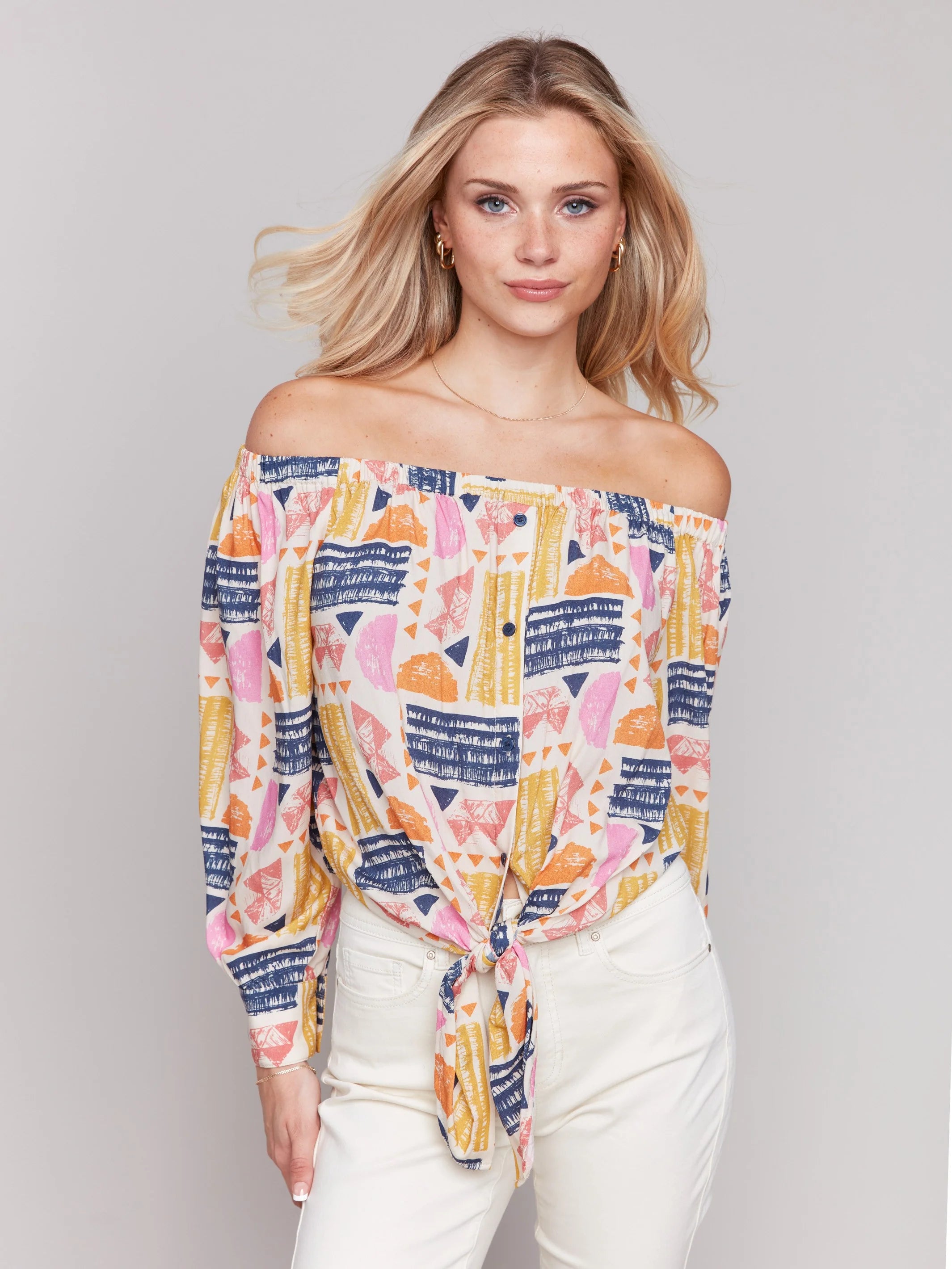 Pearls Boutique-Port Dover Ontario-Charlie B-Off-The-Shoulder Printed Blouse with Front Tie - Batik.
Vibrant off-the-shoulder blouse featuring a playful batik-inspired print. 100% viscose,lightweight and airy top,relaxed fit ,button-down front and front tie knot for a chic touch.  long sleeves.
