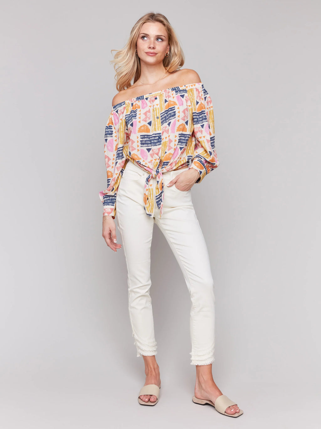 Pearls Boutique-Port Dover Ontario-Charlie B-Off-The-Shoulder Printed Blouse with Front Tie - Batik.
Vibrant off-the-shoulder blouse featuring a playful batik-inspired print. 100% viscose,lightweight and airy top,relaxed fit ,button-down front and front tie knot for a chic touch.  long sleeves.
