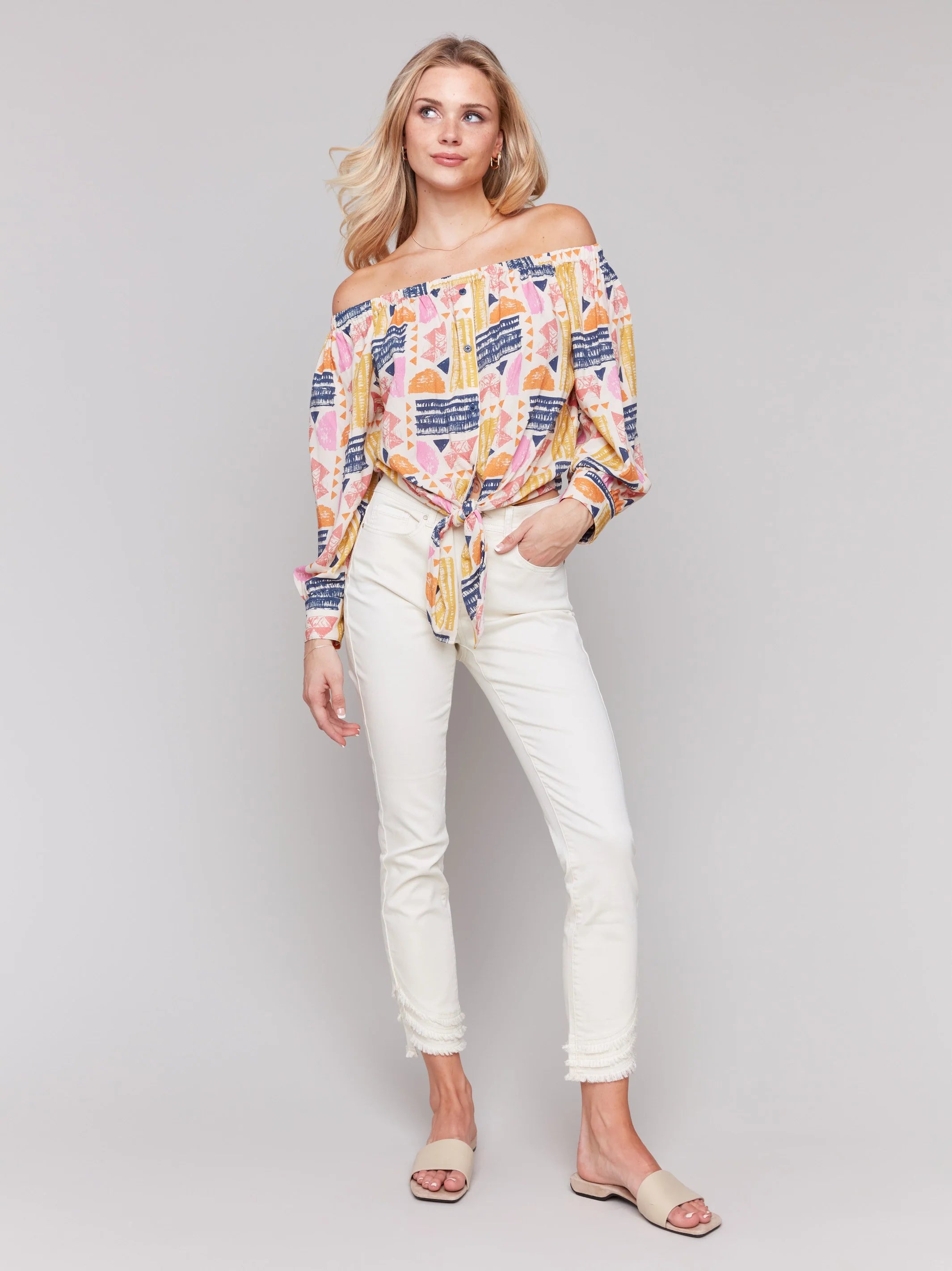 Pearls Boutique-Port Dover Ontario-Charlie B-Off-The-Shoulder Printed Blouse with Front Tie - Batik.
Vibrant off-the-shoulder blouse featuring a playful batik-inspired print. 100% viscose,lightweight and airy top,relaxed fit ,button-down front and front tie knot for a chic touch.  long sleeves.