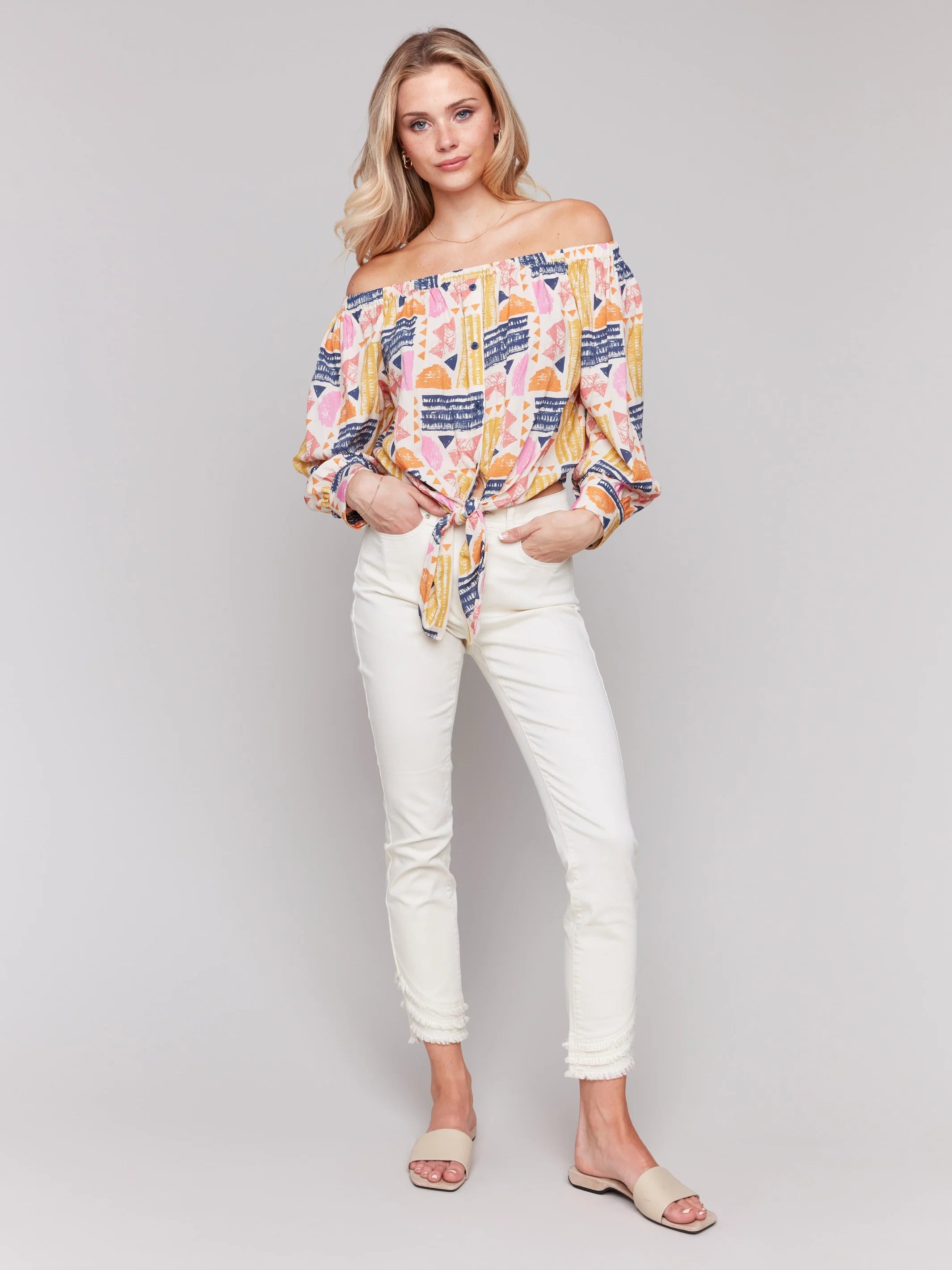 Pearls Boutique-Port Dover Ontario-Charlie B-Off-The-Shoulder Printed Blouse with Front Tie - Batik.
Vibrant off-the-shoulder blouse featuring a playful batik-inspired print. 100% viscose,lightweight and airy top,relaxed fit ,button-down front and front tie knot for a chic touch.  long sleeves.