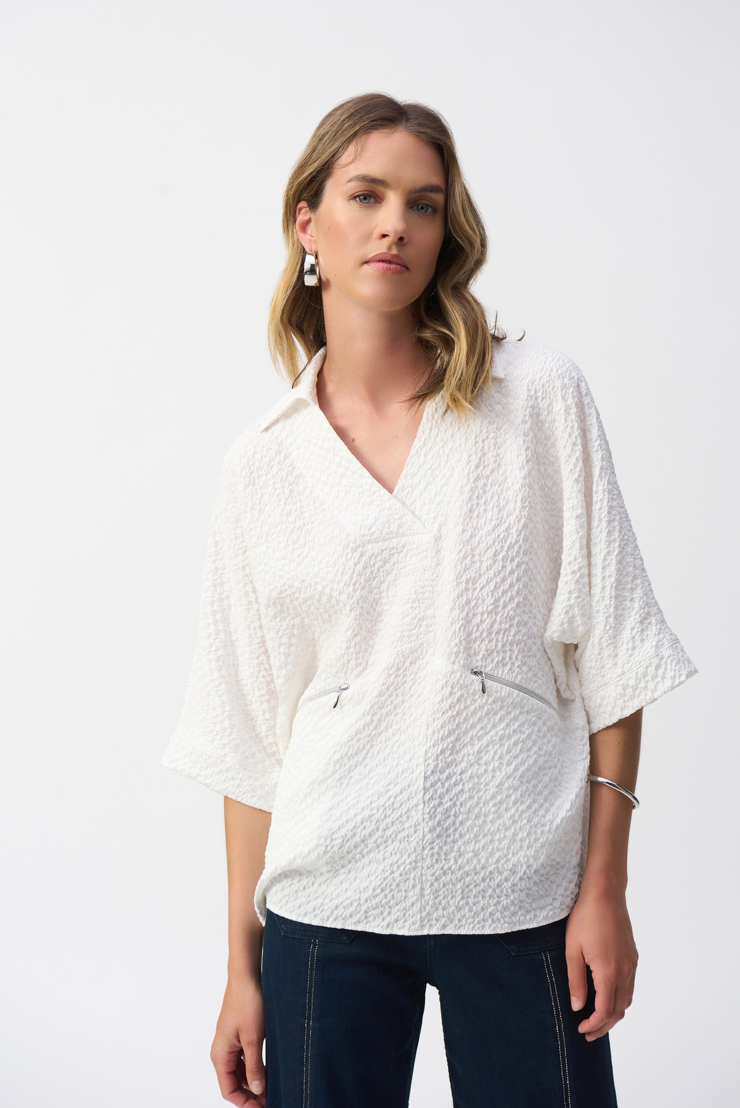 Pearls Boutique-Port Dover Ontario-Joseph Ribkoff - Seersucker Boxy High-Low Top-251165-12. a ivory pullover featuring a chic, minimalistic design with a textured seersucker finish. This hip-length, relaxed-fit piece offers a sophisticated V-neckline, short 3/4 drop sleeves, and front pockets for added functionality. Unlined for a lightweight feel, making it perfect for casual or office wear. Crafted from a soft blend of polyester, viscose rayon, and spandex for comfort and elegance.