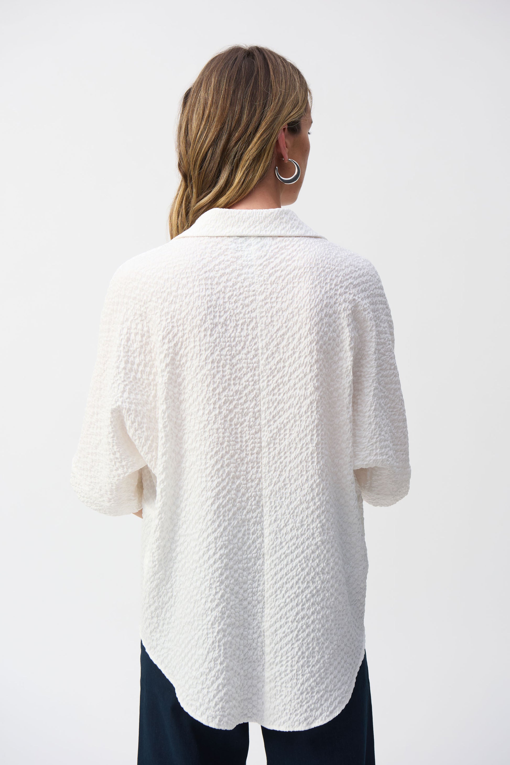 Joseph Ribkoff pullover featuring a chic, minimalistic design with a textured seersucker finish. This hip-length, relaxed-fit piece offers a sophisticated V-neckline, short 3/4 drop sleeves, and front pockets for added functionality. Unlined for a lightweight feel, making it perfect for casual or office wear. Crafted from a soft blend of polyester, viscose rayon, and spandex for comfort and elegance.