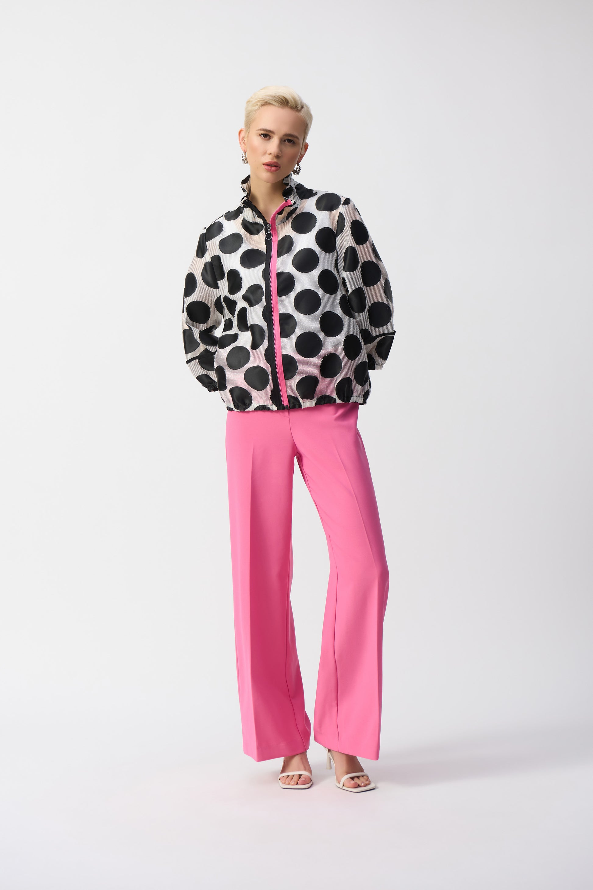 Pearls Boutique-Port Dover Ontario-Joseph Ribkoff Jacket 251123 – Black-and-white polka dot jacket with pink zipper accent, made from a lightweight 70% polyester, 15% acrylic, and 15% nylon blend. Relaxed fit with elastic hem for versatile styling. Perfect for casual, work, or evening wear. Made in Canada.