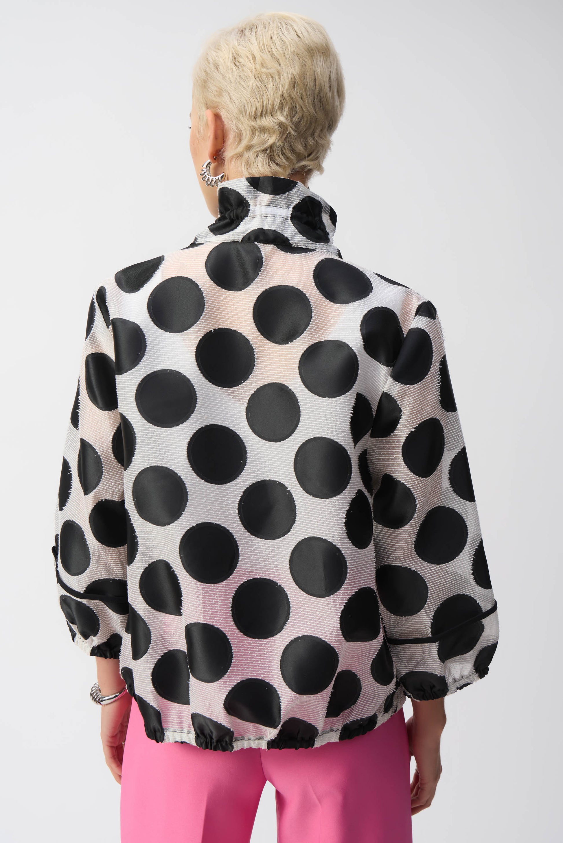 Pearls Boutique-Port Dover Ontario-Joseph Ribkoff Jacket 251123 – Black-and-white polka dot jacket with pink zipper accent, made from a lightweight 70% polyester, 15% acrylic, and 15% nylon blend. Relaxed fit with elastic hem for versatile styling. Perfect for casual, work, or evening wear. Made in Canada.