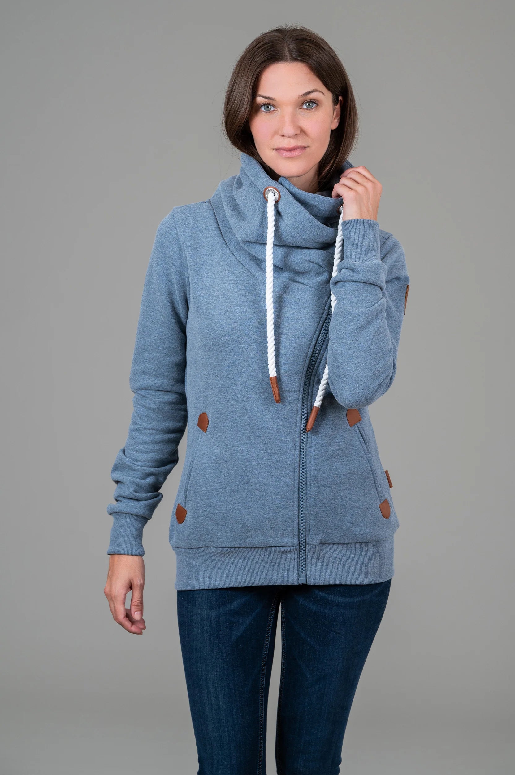 Pearls Boutique-Port Dover Ontario-Wanakome Hestia full-zip sweatshirt-Heather Blue. featuring a contoured fit and soft French terry fabric with a brushed interior. Includes an adjustable hood with thick rope drawstrings and vegan leather caps, a full-length asymmetrical zipper, and ribbed cuffs and hem. Finished with vegan leather Wanakome patch logos on the chest and sleeve, plus roomy front pockets for added comfort.