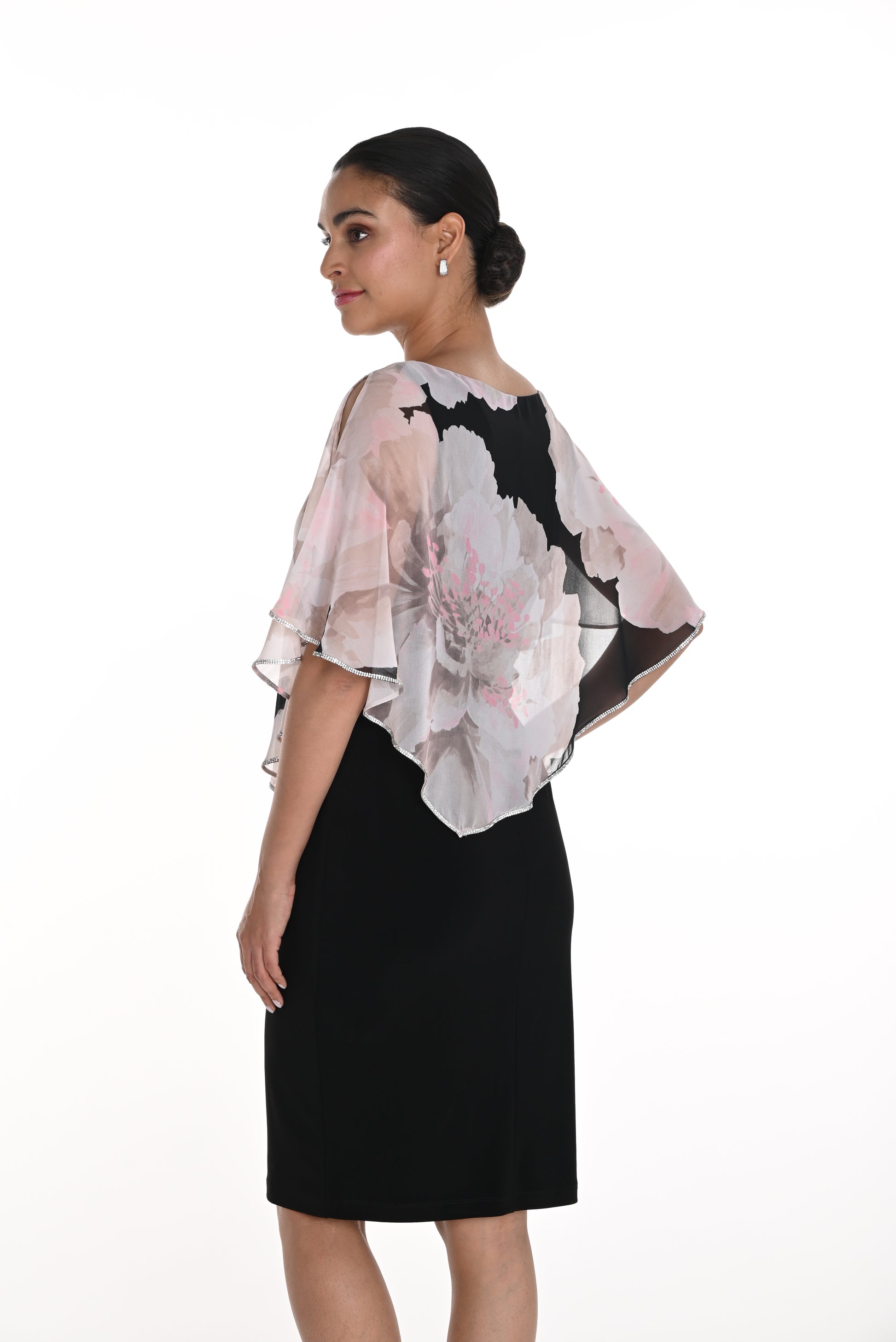 Pearls Boutique-Port Dover Ontario Frank Lyman Knee-Length Dress – Elegant and sophisticated design.
 
Chiffon Cape Overlay – Sheer, flowing fabric drapes over the shoulders.
Floral Print on Cape – Large soft grey and pink flowers with black accents.
Asymmetrical Hem on Cape – Adds movement and a touch of drama.
Boat Neckline –
Short Flutter Sleeves – Light and airy chiffon drapes over arms.
 Trim on Cape Edge has Subtle shimmer Ideal for weddings, parties, or elegant gatherings.






