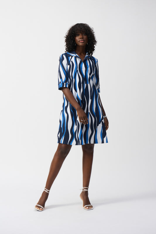 Pearls Boutique- Port Dover Ontario-Joseph Ribkoff- Making waves dress- 251294-Knee-Length Shift Dress, relaxed shift dress fit, knee length, abstract pattern, notched-collar neckline, 3/4 straight sleeves, button accents, side pockets, lightweight fabric, travel-friendly, summer sundress, effortless style, perfect for beach days, casual outings, or layering with a denim jacket and sneakers. Pattern tones of beautiful blue on a white base 







