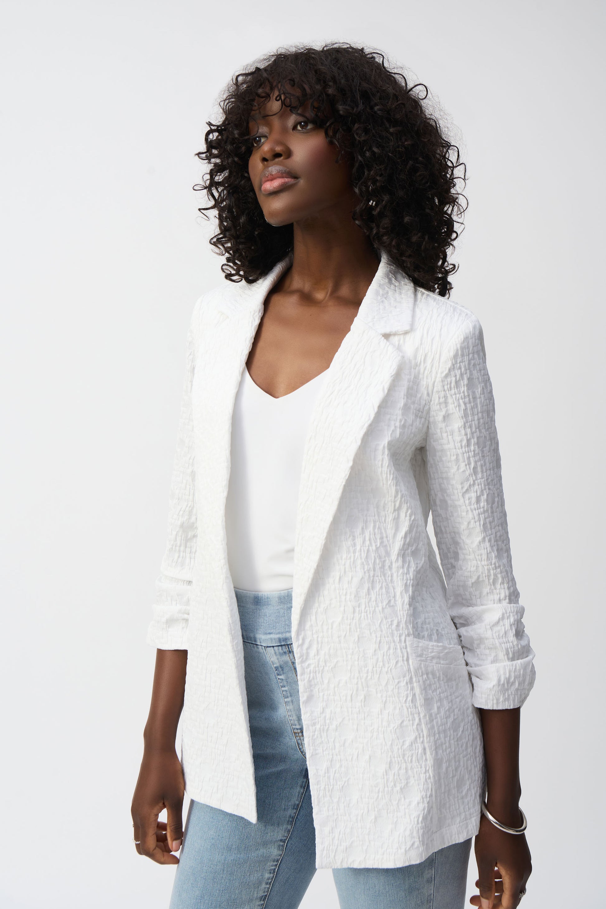 Pearls Boutique- Port Dover Ontario-Joseph Ribkoff White Textured Blazer 242034 Open-front jacket with a polished yet relaxed silhouette for effortless layering, featuring a sophisticated notched lapel for both office and casual wear. Designed with long, straight sleeves for versatile all-season styling. Functional side pockets add practicality without compromising style. Made from a soft, breathable blend of 99% polyester and 1% spandex for all-day comfort.