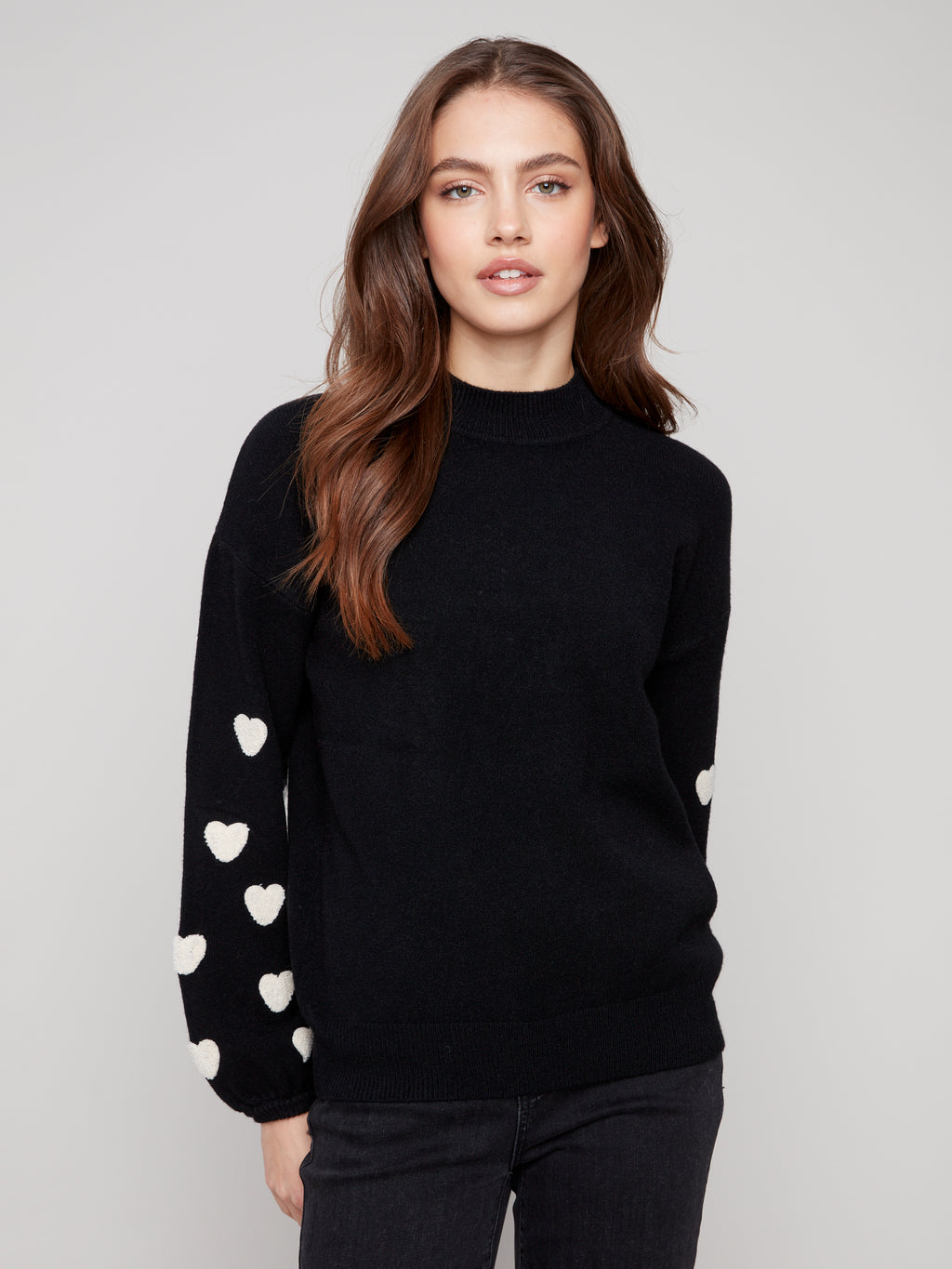 Pearls Boutique | Port Dover Ontario|Charlie B | Mock Neck Sweater With Embroidered Hearts| colour black with white embroidered hearts on sleeves. Mock neck sweater in a soft plush knit, featuring heart embroidery on balloon sleeves, relaxed fit.