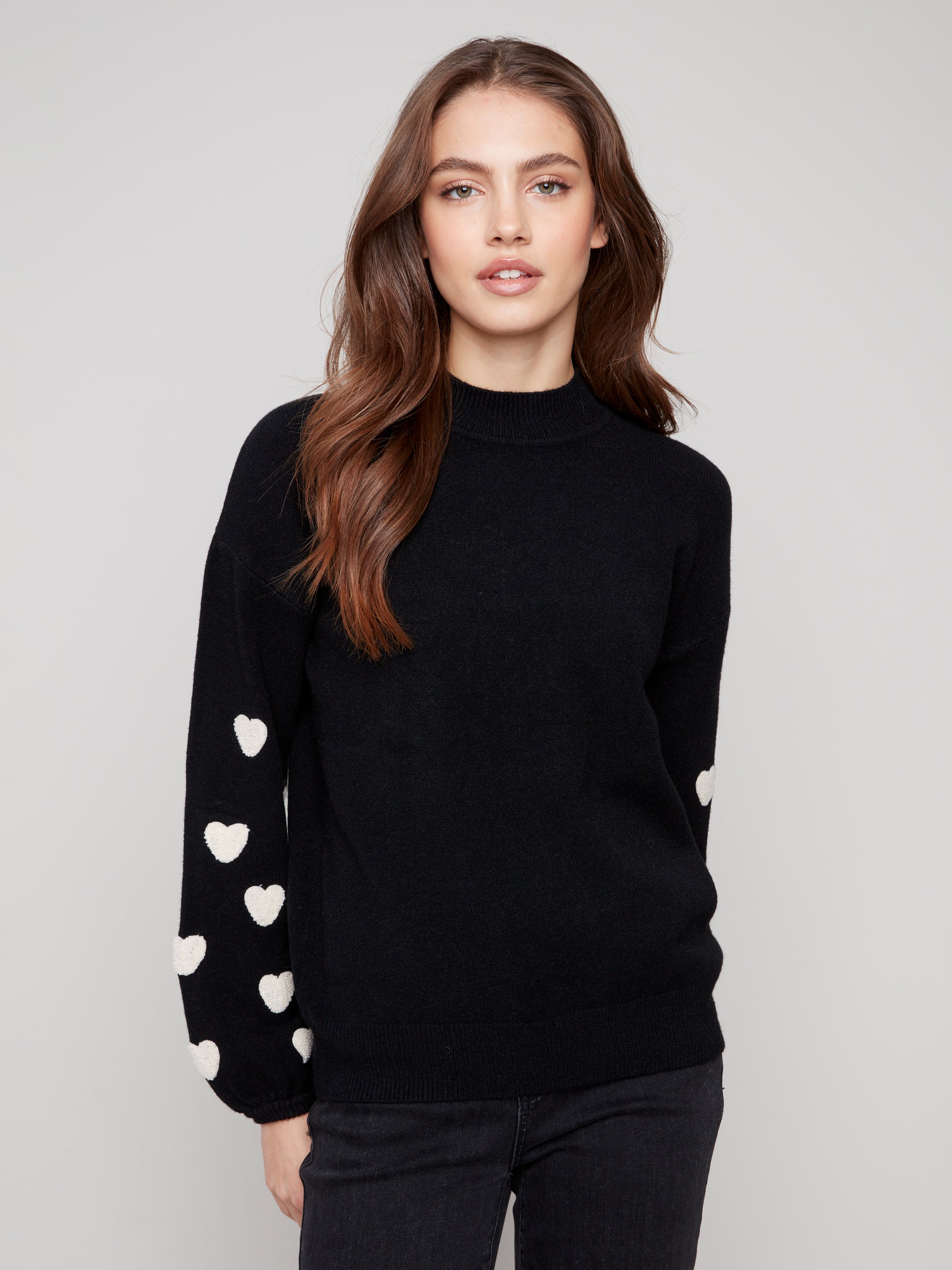 Pearls Boutique | Port Dover Ontario|Charlie B | Mock Neck Sweater With Embroidered Hearts| colour black with white embroidered hearts on sleeves. Mock neck sweater in a soft plush knit, featuring heart embroidery on balloon sleeves, relaxed fit.
