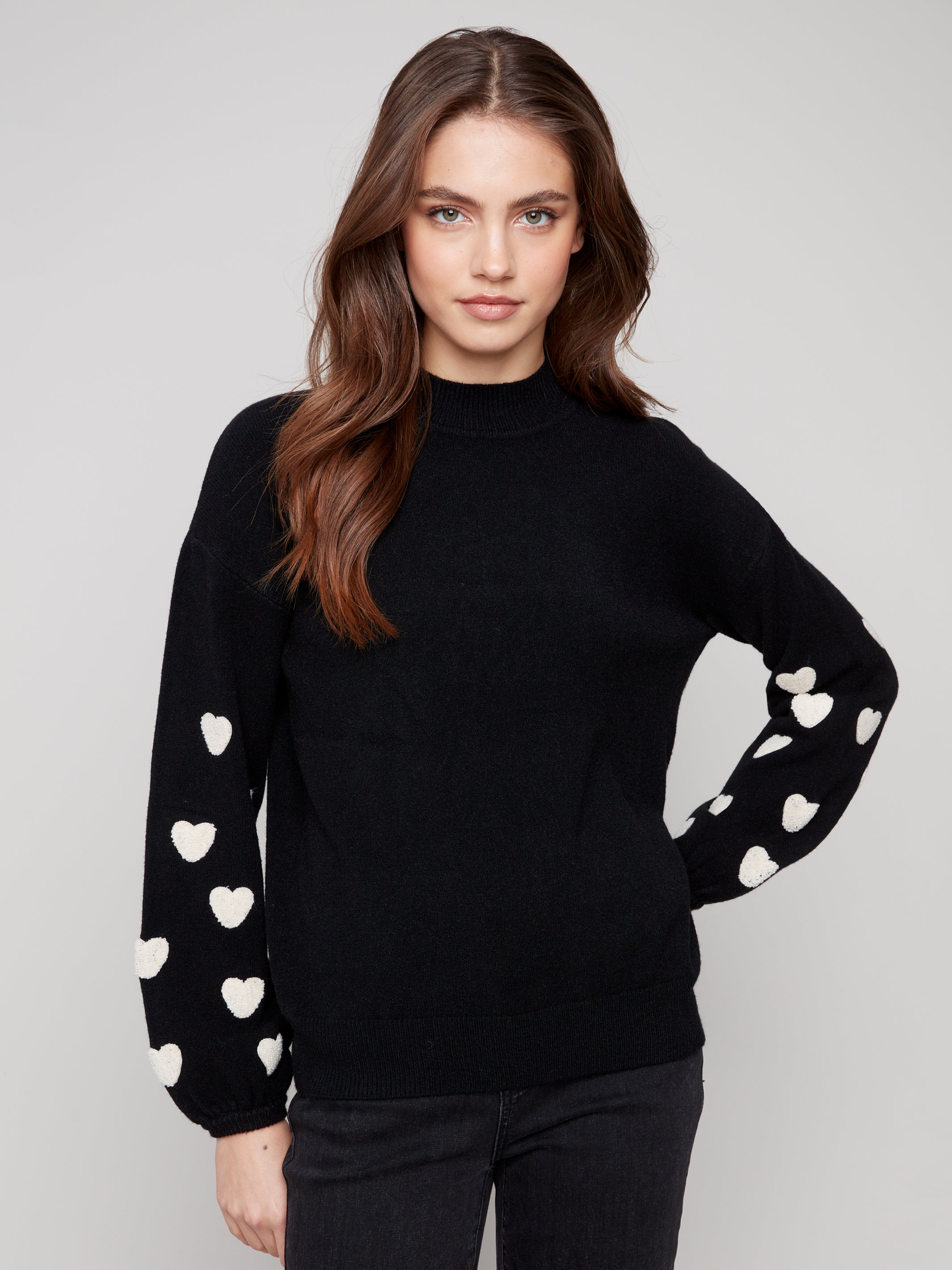 Pearls Boutique | Port Dover Ontario|Charlie B | Mock Neck Sweater With Embroidered Hearts| colour black with white embroidered hearts on sleeves. Mock neck sweater in a soft plush knit, featuring heart embroidery on balloon sleeves, relaxed fit.