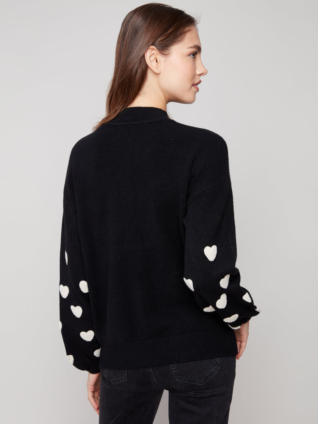 Pearls Boutique | Port Dover Ontario|Charlie B | Mock Neck Sweater With Embroidered Hearts| colour black with white embroidered hearts on sleeves. Mock neck sweater in a soft plush knit, featuring heart embroidery on balloon sleeves, relaxed fit.