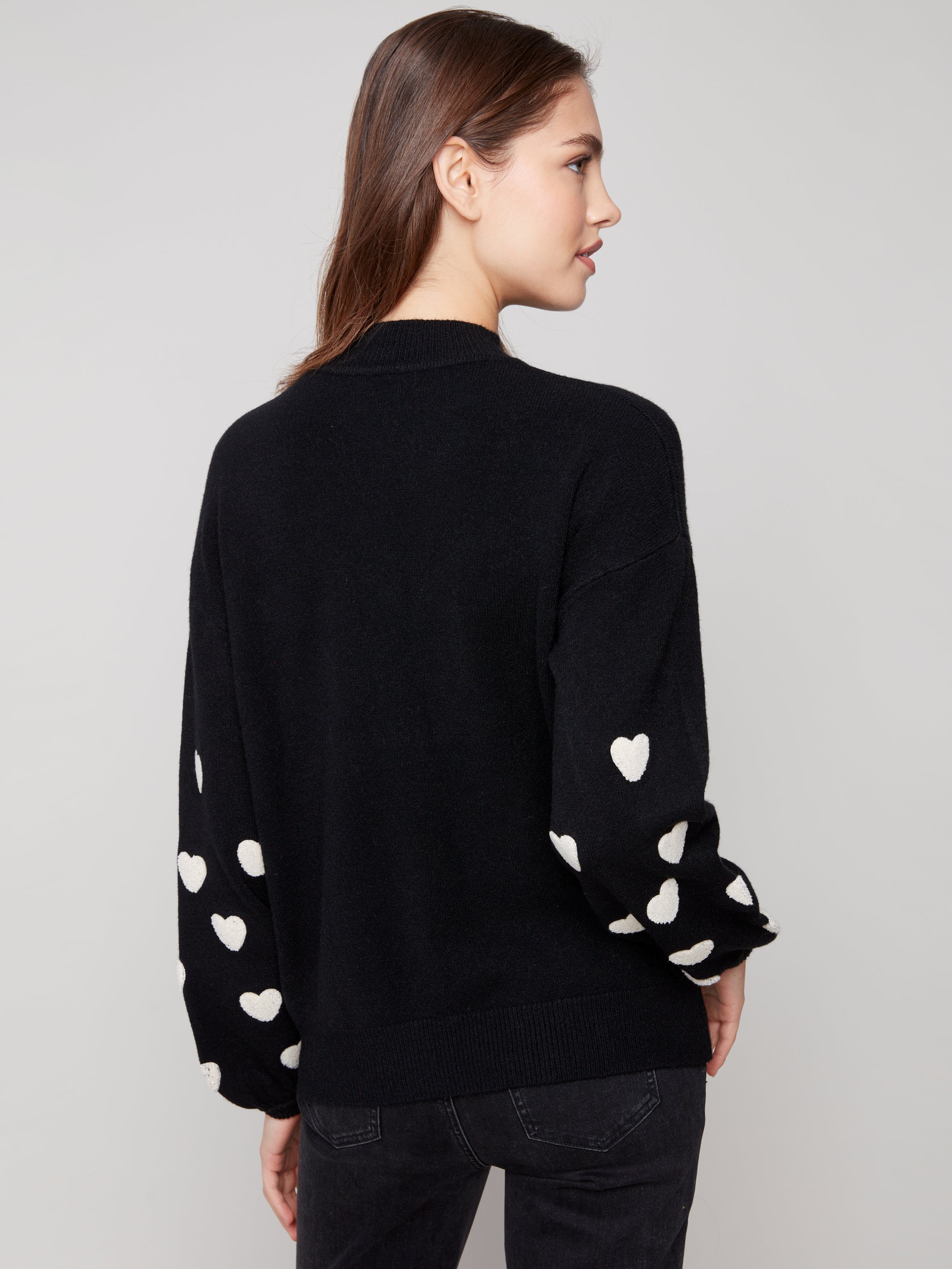 Pearls Boutique | Port Dover Ontario|Charlie B | Mock Neck Sweater With Embroidered Hearts| colour black with white embroidered hearts on sleeves. Mock neck sweater in a soft plush knit, featuring heart embroidery on balloon sleeves, relaxed fit.