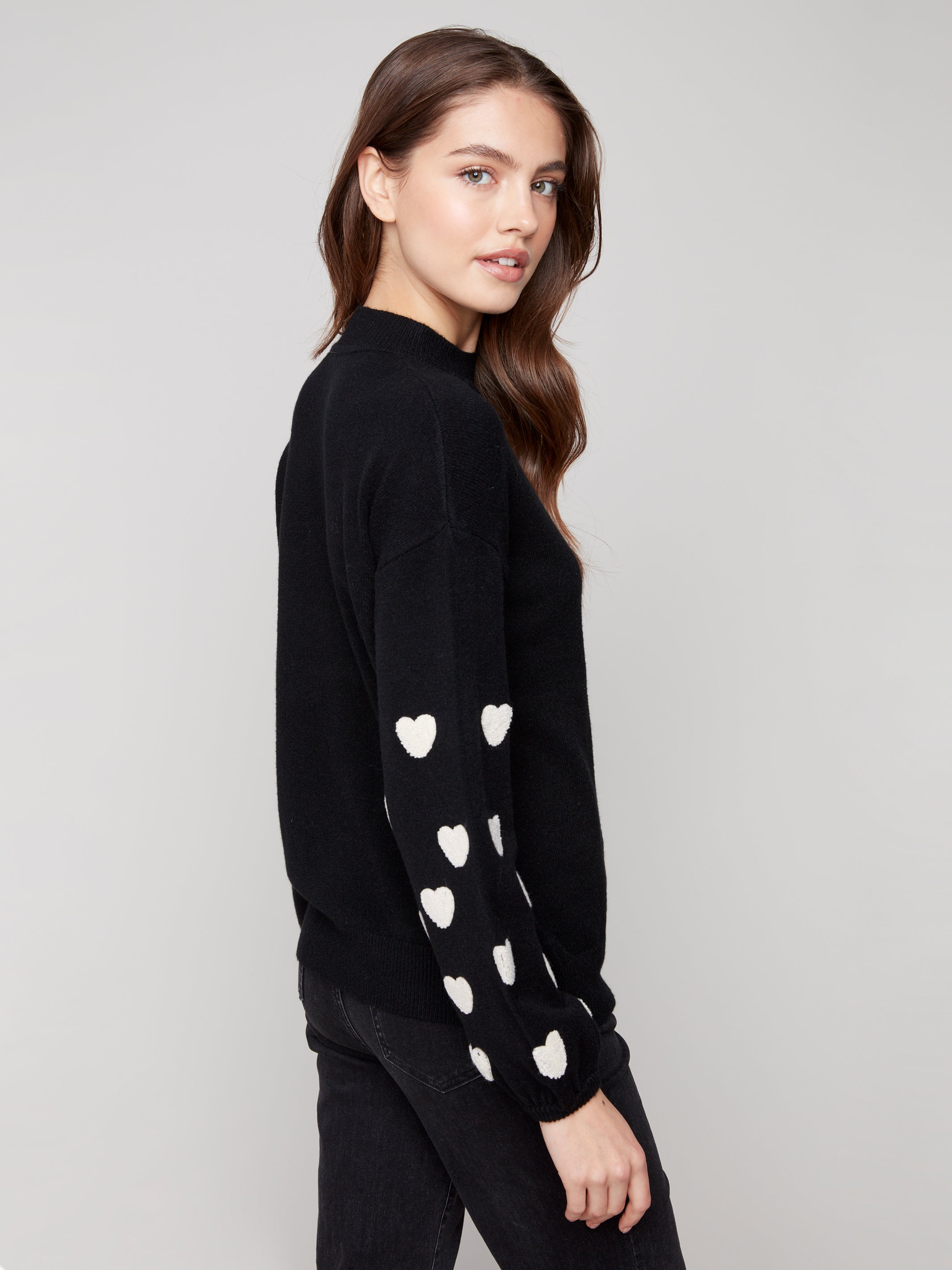 Pearls Boutique | Port Dover Ontario|Charlie B | Mock Neck Sweater With Embroidered Hearts| colour black with white embroidered hearts on sleeves. Mock neck sweater in a soft plush knit, featuring heart embroidery on balloon sleeves, relaxed fit.