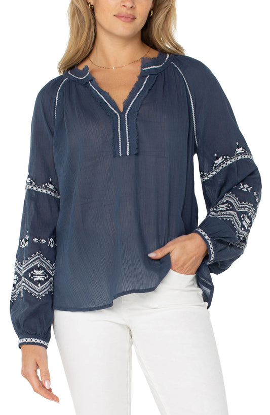Pearls Boutique| Port Dover Ontario| Liverpool |  Longsleeve Raglan Woven Blouse|LM8F83WV57E1 A dark dusty blue embroidered woven top featuring white embroidery along the raglan sleeves and V-neckline. The top has long raglan sleeves, a V-neck design, and a relaxed, lightweight fit made from 100% cotton