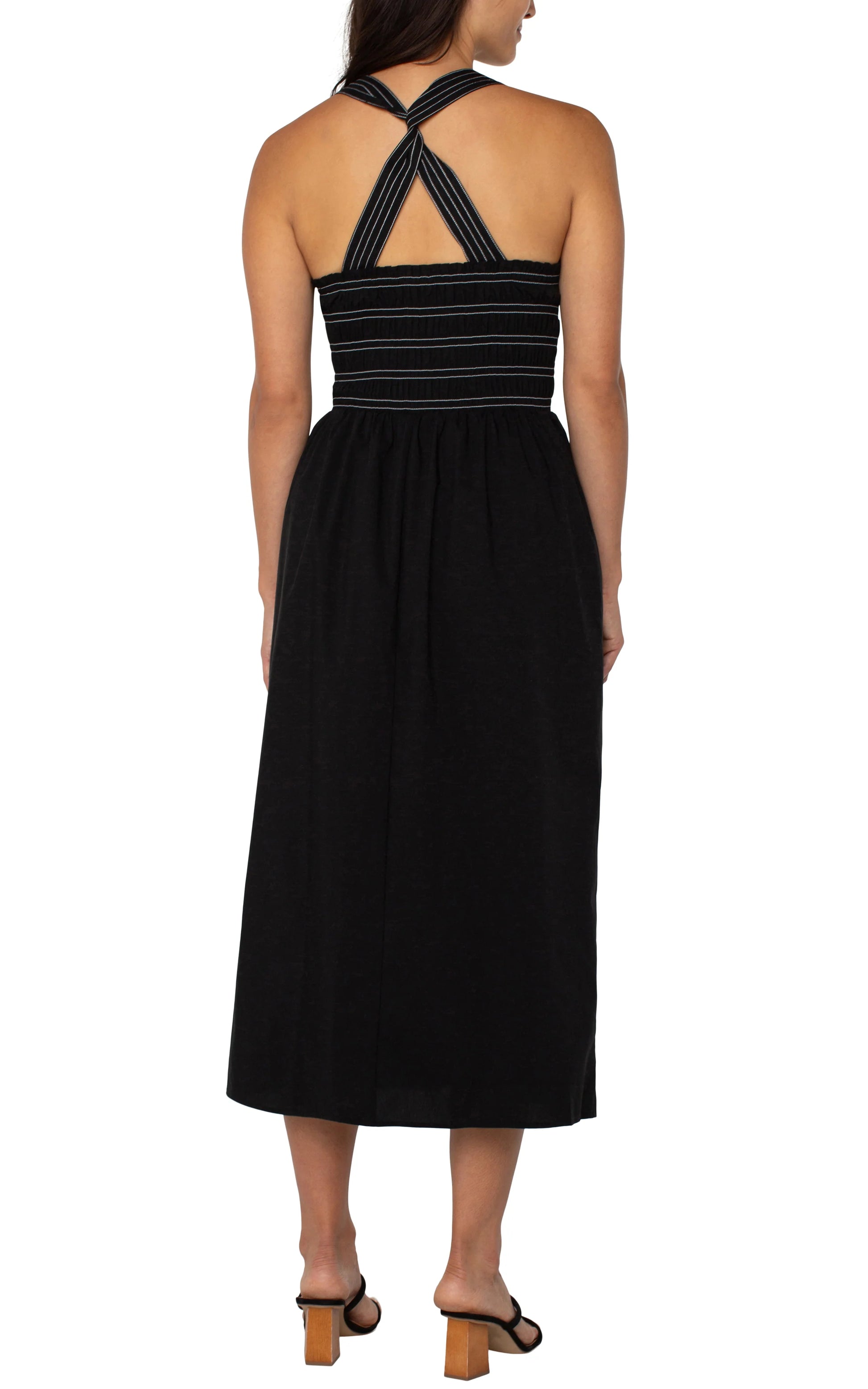 Pearls Boutique|Port Dover Ontario| Liverpool|Sleeveless Smocked Midi Dress|Black with white  stripe accent on straps and bodice.
A sleeveless black midi length dress featuring a smocked bodice with white detailing. The dress has removable shoulder straps, two side pockets, and an A-line silhouette. Made from a blend of 67% cotton, 29% polyester, and 4% spandex, it offers a comfortable, stretchy fit. The dress is 42-1/2" from the high point of the shoulder.