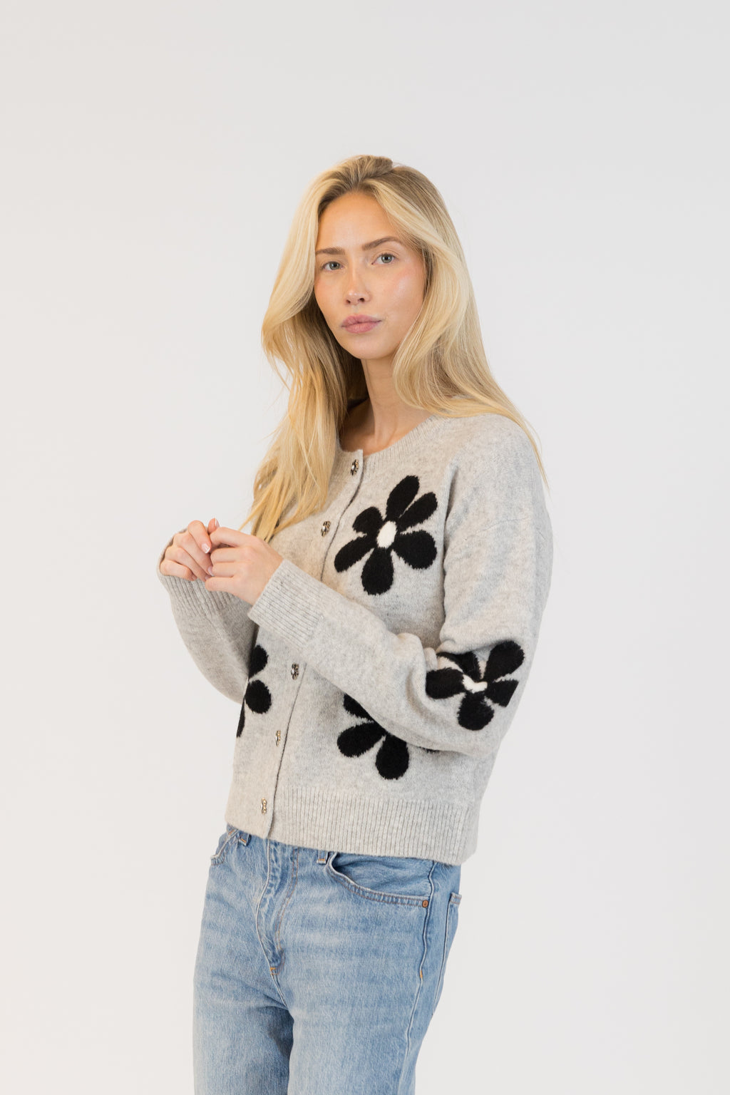 Pearls Boutique| Port Dover Ontario|Lyla + Lux|Lyla + Lux women’s crew neck cardigan named Jorgie, featuring black daisies scattered across a soft  grey melange knit fabric. classic crew neckline, long sleeves, relaxed fit, this cardigan is finished with delicate little black daisy enamel buttons down the front. Crafted from a lightweight, easy-care blend of polyester, acrylic, polyamide, wool, and elastane, 