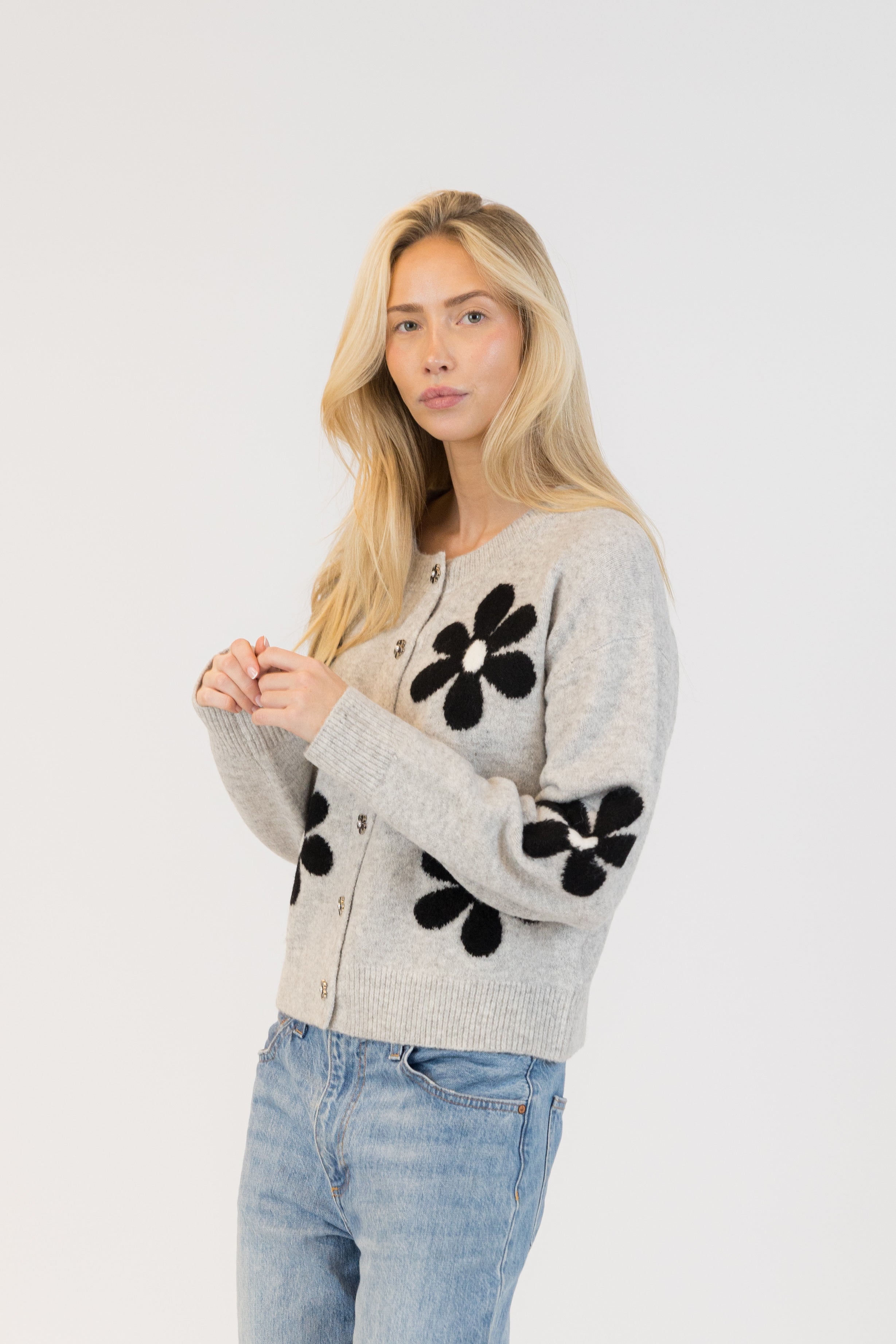 Pearls Boutique| Port Dover Ontario|Lyla + Lux|Lyla + Lux women’s crew neck cardigan named Jorgie, featuring black daisies scattered across a soft  grey melange knit fabric. classic crew neckline, long sleeves, relaxed fit, this cardigan is finished with delicate little black daisy enamel buttons down the front. Crafted from a lightweight, easy-care blend of polyester, acrylic, polyamide, wool, and elastane, 