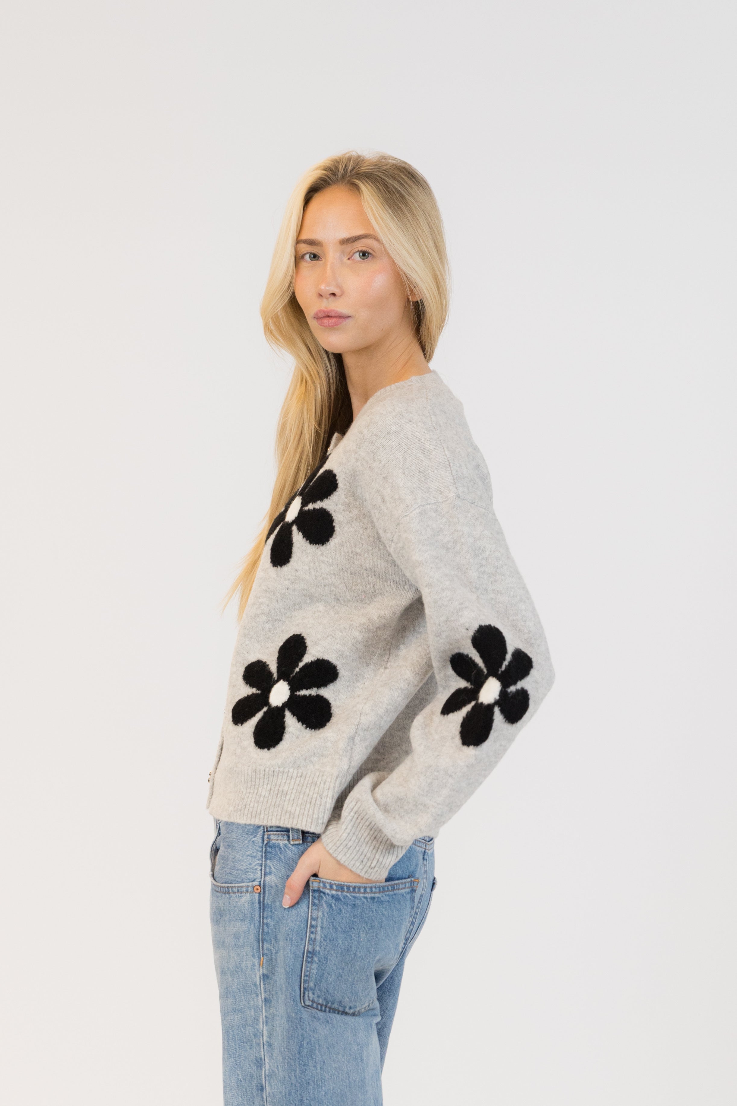 Pearls Boutique| Port Dover Ontario|Lyla + Lux|Lyla + Lux women’s crew neck cardigan named Jorgie, featuring black daisies scattered across a soft  grey melange knit fabric. classic crew neckline, long sleeves, relaxed fit, this cardigan is finished with delicate little black daisy enamel buttons down the front. Crafted from a lightweight, easy-care blend of polyester, acrylic, polyamide, wool, and elastane