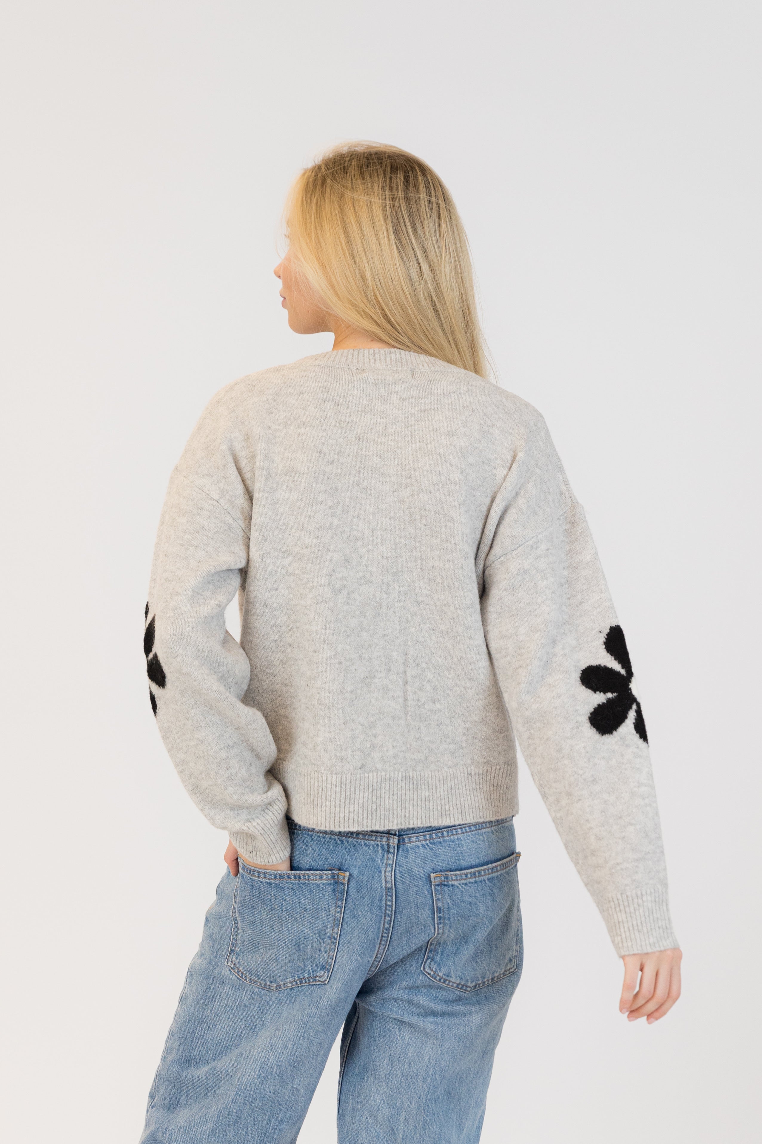 Pearls Boutique| Port Dover Ontario|Lyla + Lux|Lyla + Lux women’s crew neck cardigan named Jorgie, featuring black daisies scattered across a soft  grey melange knit fabric. classic crew neckline, long sleeves, relaxed fit, this cardigan is finished with delicate little black daisy enamel buttons down the front. Crafted from a lightweight, easy-care blend of polyester, acrylic, polyamide, wool, and elastane