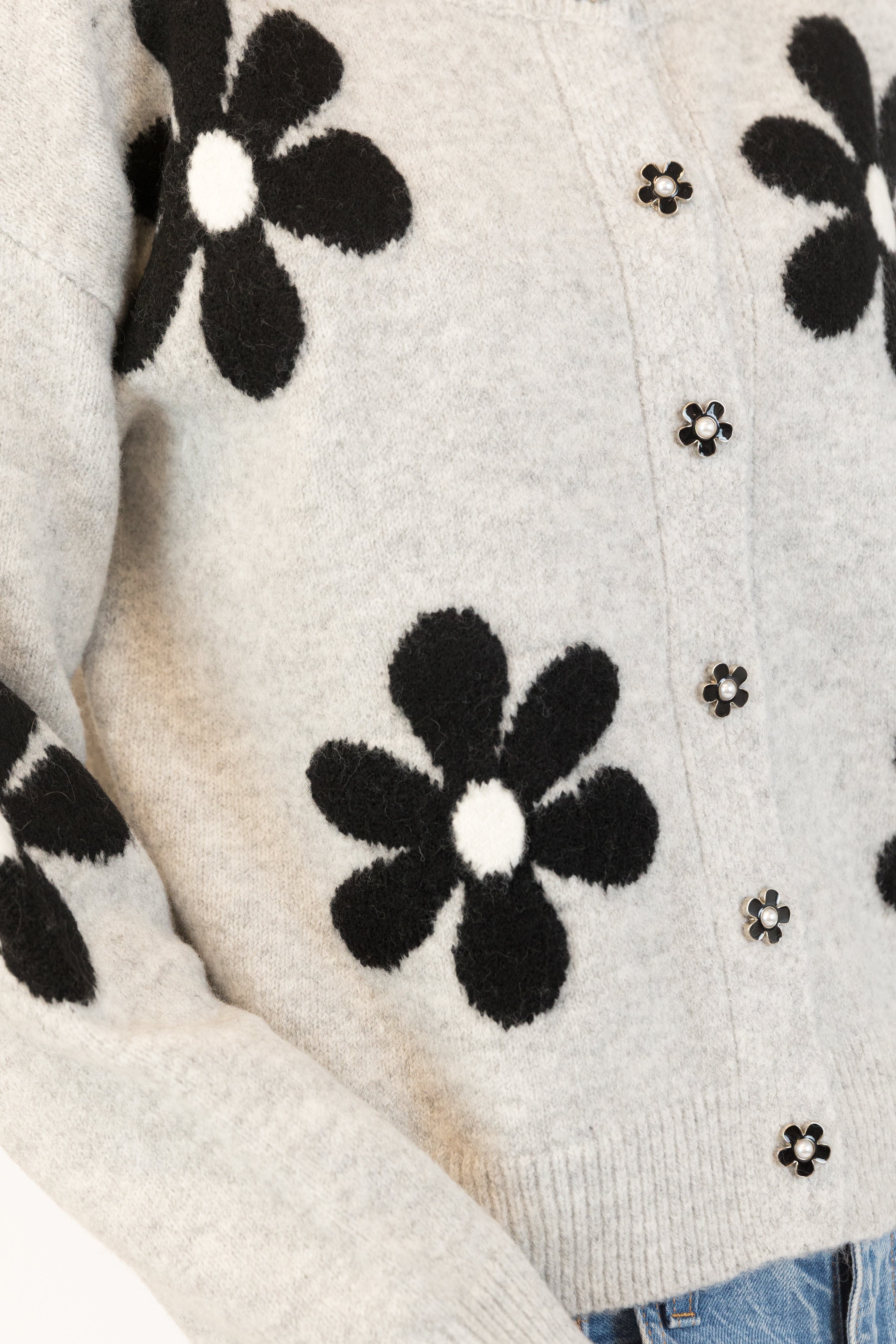 Pearls Boutique| Port Dover Ontario|Lyla + Lux|Lyla + Lux women’s crew neck cardigan named Jorgie, featuring black daisies scattered across a soft  grey melange knit fabric. classic crew neckline, long sleeves, relaxed fit, this cardigan is finished with delicate little black daisy enamel buttons down the front. Crafted from a lightweight, easy-care blend of polyester, acrylic, polyamide, wool, and elastane, 