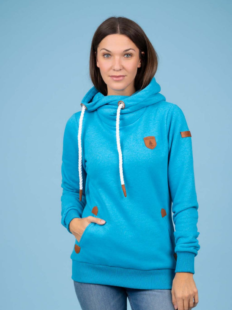 Woman wearing a blue hoodie with brown accents on a light blue background. Pearls Boutique, Port Dover, Ontario.